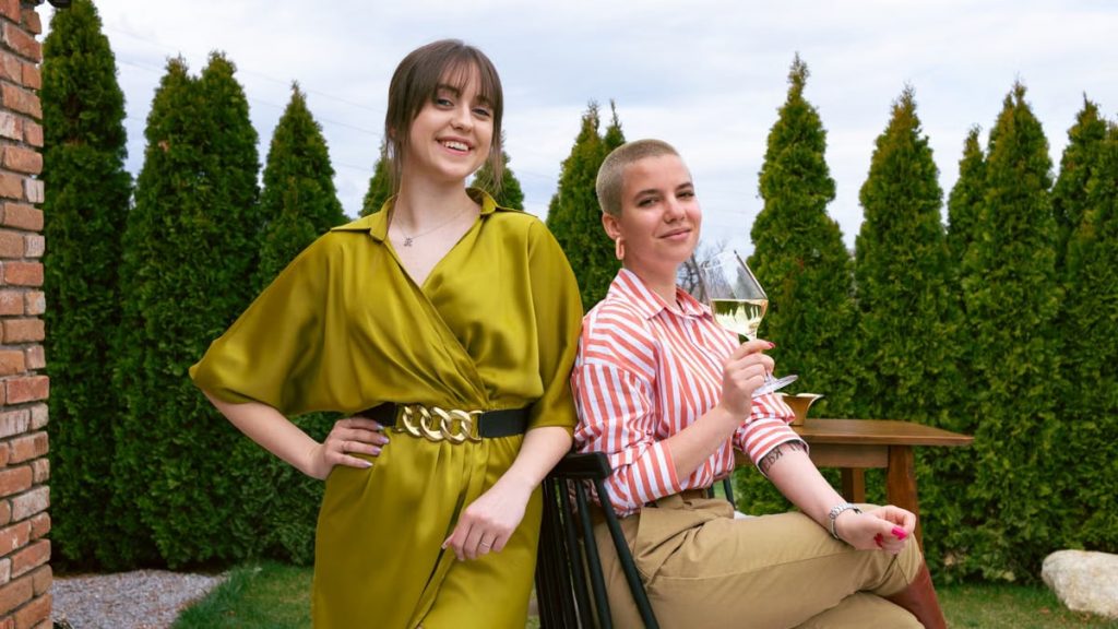 Two women enjoying a relaxing time outdoors, sharing smiles and wine.