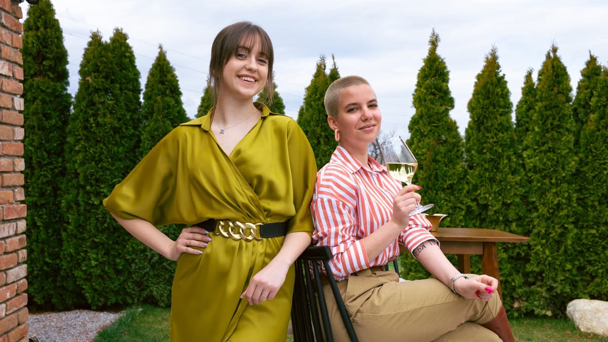 Two women enjoying a relaxing time outdoors, sharing smiles and wine.